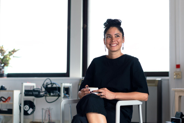 Woman sitting relaxed in a chair holding a cup, smiling in a bright office setting