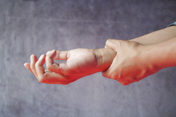 Close-up of one hand grasping the other, indicating joint discomfort