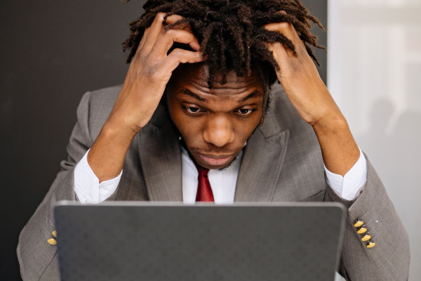 Exhausted man in a suit sitting at his laptop, showing signs of fatigue