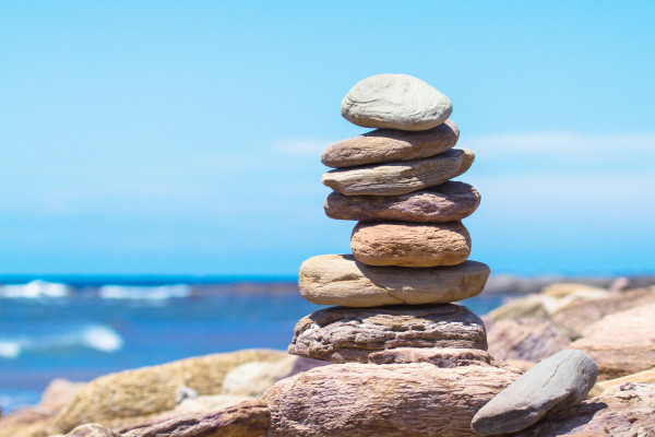 A stack of smooth balanced stones against a soft blue background, symbolising equilibrium.
