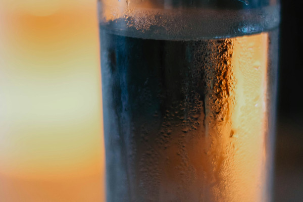 A clear glass of water catching the light, with visible reflections and droplets.