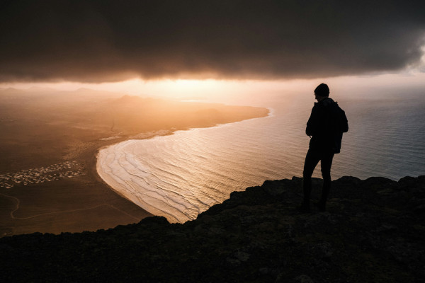 A silhouette of a person standing and looking out toward the horizon.