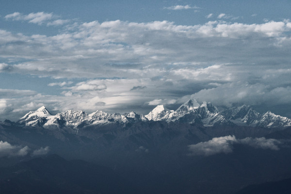 A mountain summit rising above the clouds under a pale sky.