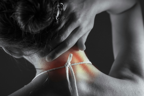 Close-up of a woman's neck and shoulder, with the site of her back and neck pain highlighted