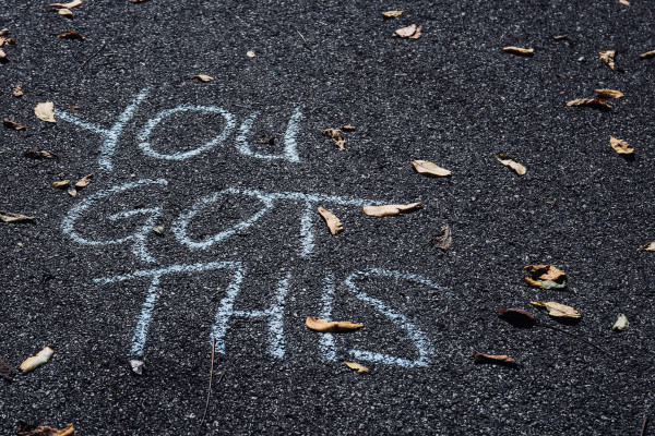 A handwritten 'you got this' encouragement message written in chalk on pavement