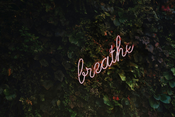 A neon sign reading "…breathe!" glowing softly against a dark background.