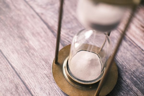 An hourglass sitting on a wooden table, measuring the passage of time.