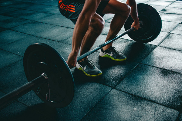 A person preparing to lift a loaded barbell off the ground.