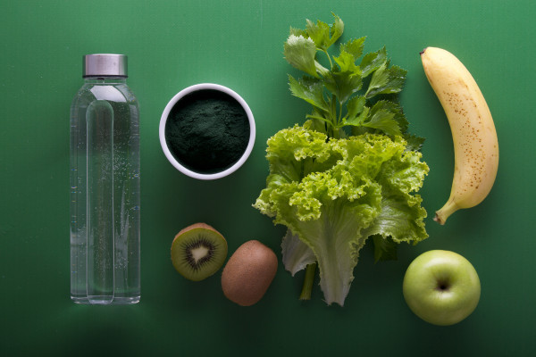 An assortment of colourful fresh fruits and vegetables arranged on a green surface.