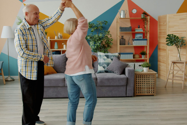 An elderly couple dancing joyfully together in their living room.