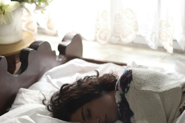 A woman asleep in bed beside an open book, reflecting a calming pre-sleep reading routine